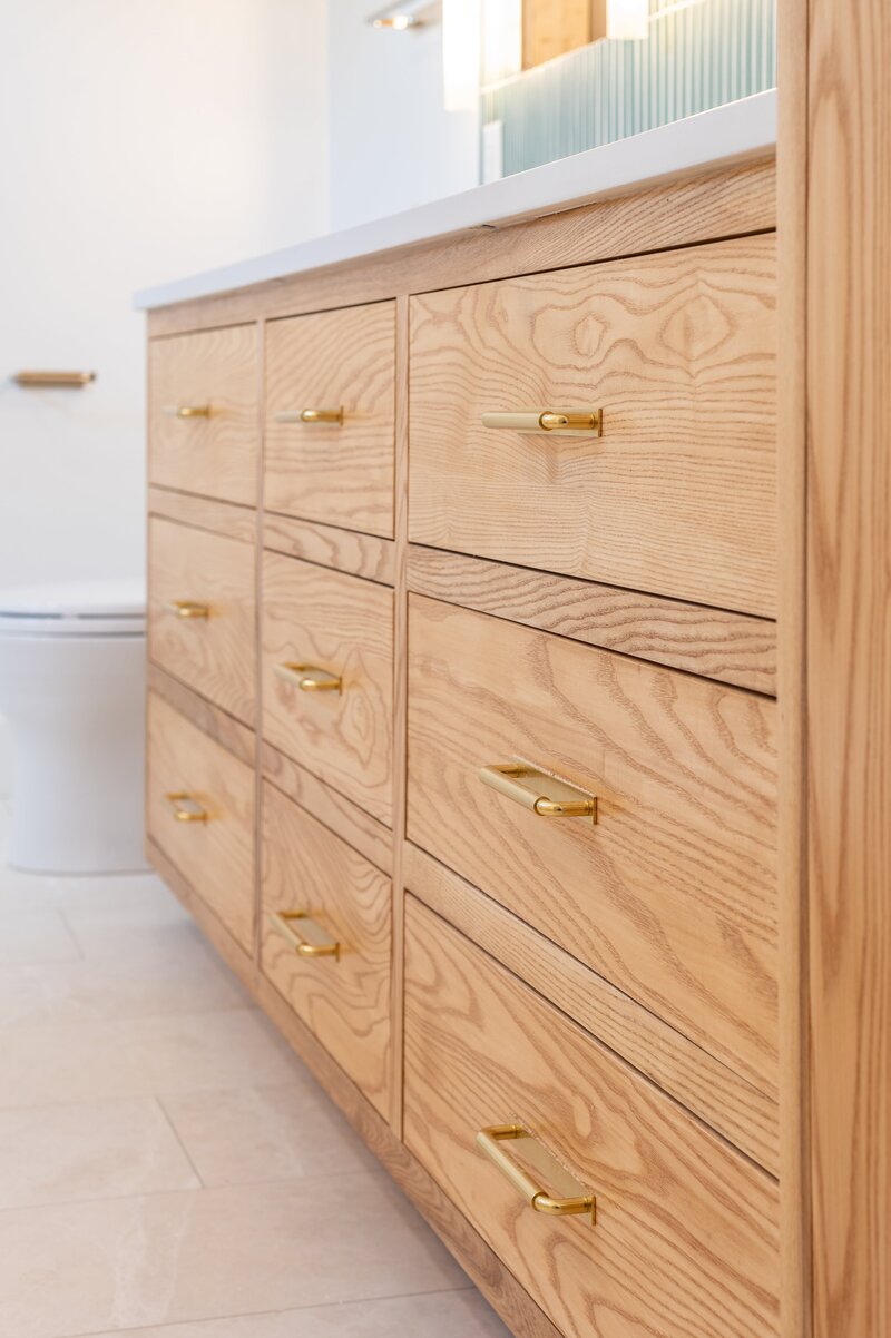 Close-up view of custom wooden drawers in a modern bathroom, showcasing the natural grain and sleek design of the cabinetry