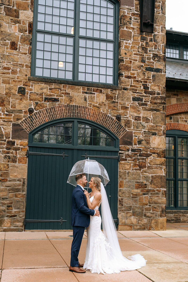 bride and groom under umbrella outside