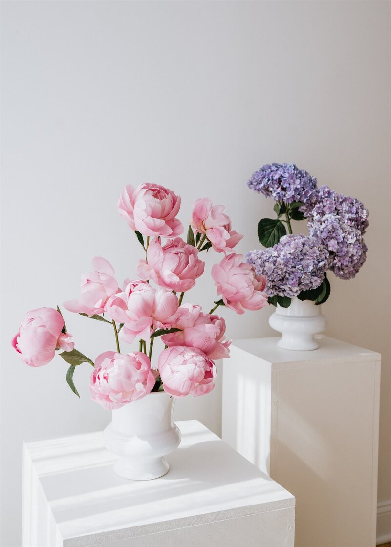 Vase of pink peonies and a vase of purple hydrangeas