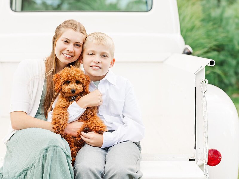 Kids holding a puppy and sitting in a 1951 Ford truck.