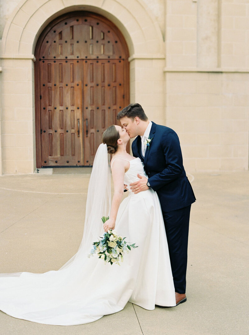 Bride and groom share a kiss after their wedding ceremony at St. Martin De Porres Catholic Church in Lake Charles, captured by Morgan Alysse, Lafayette wedding photographer.