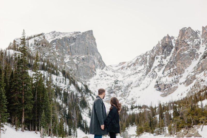 Couple admiring the breathtaking view of Dream Lake in Rocky Mountain National Park, Estes Park, during their engagement session.