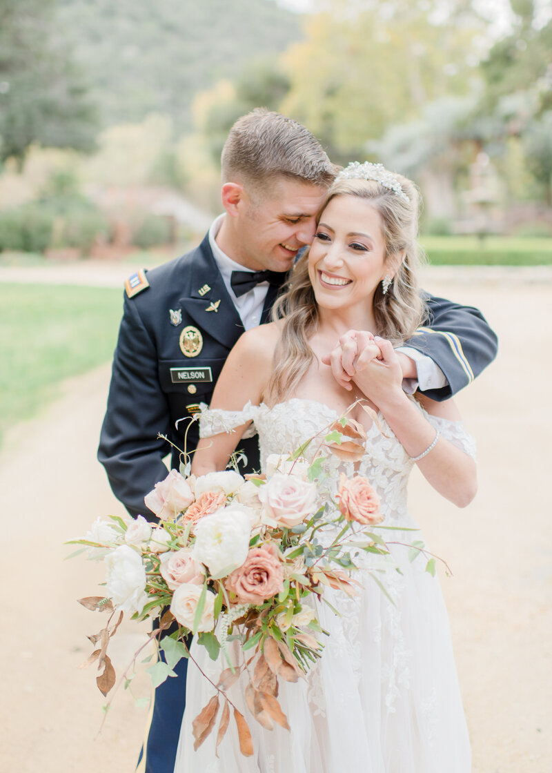 groom holding his bride and snuggling into her while they laugh and smie. 