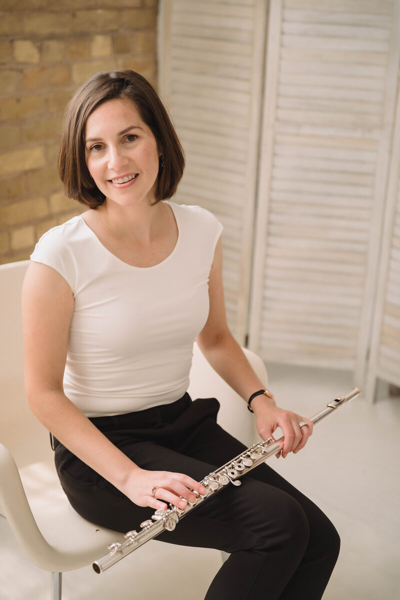 Sarah Weisbrod, Flutist & Teaching Artist, Sitting in a White Chair with Flute