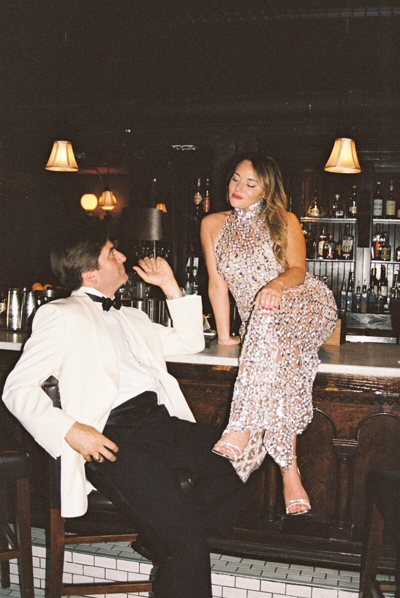 A bride and groom hang out on a bar smiling at each other