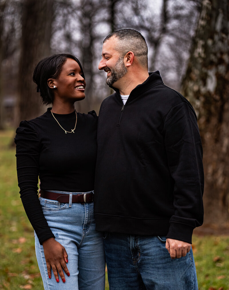 man and woman posing in the woods looking into eachothers eyes