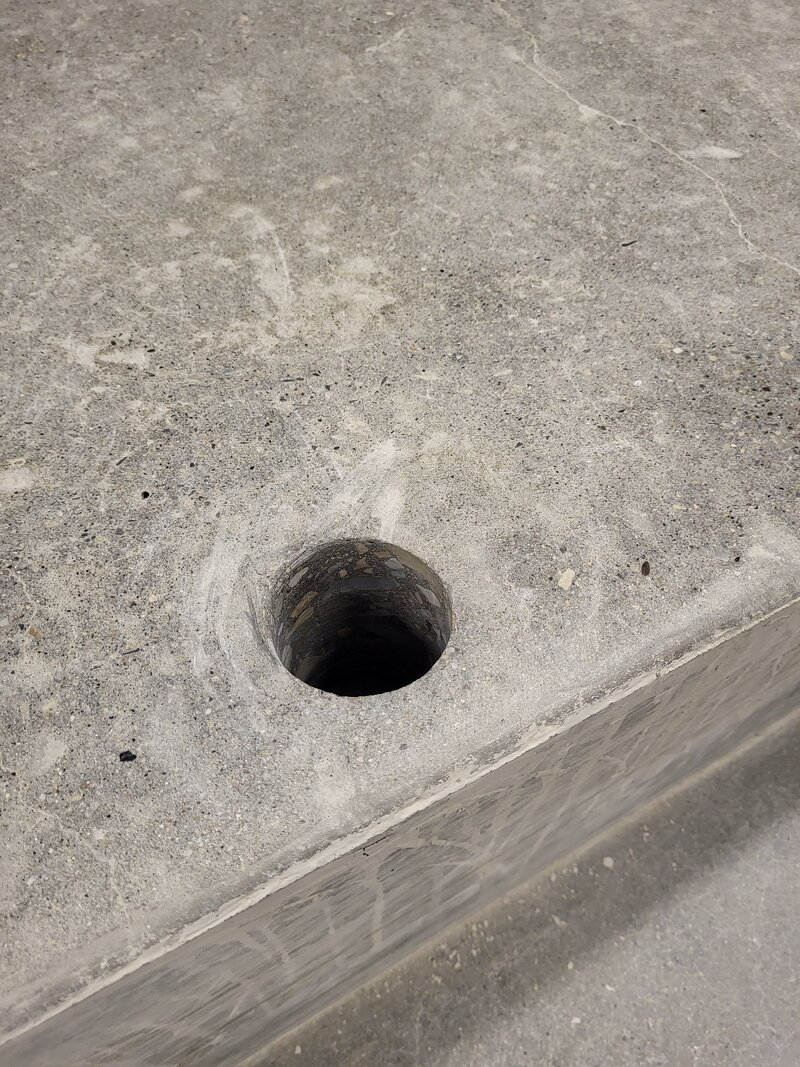 A finished circular hole that has been cored out of a slab of concrete