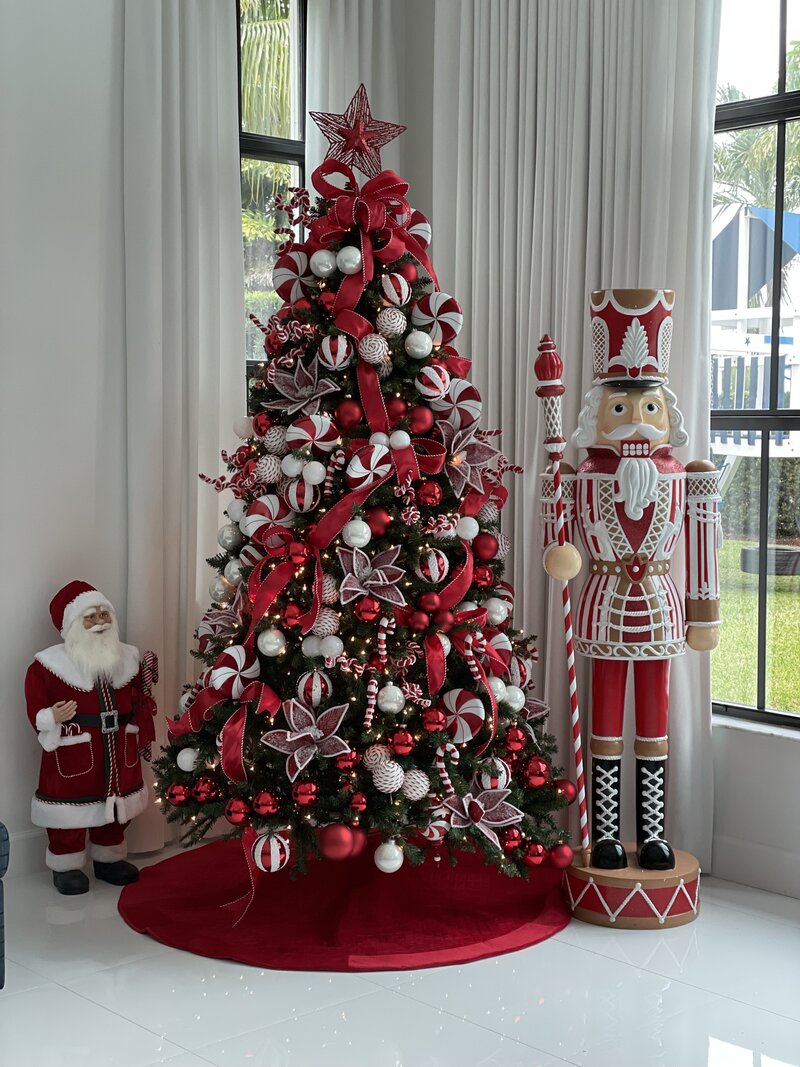 Christmas tree decorated in red and white ornaments with a star topper, styled with Santa and nutcracker figures, showcasing holiday signature styling by Interiors by CV.