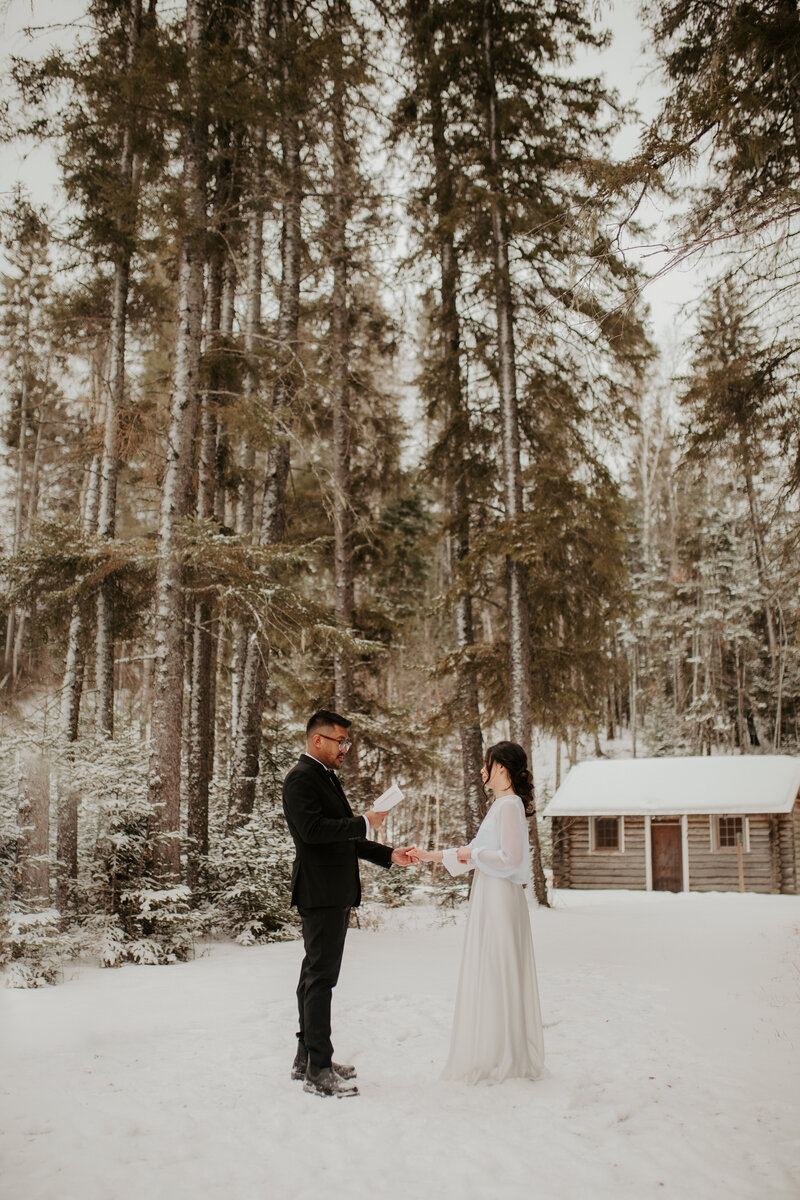 bride and groom holding hands in front of cabin