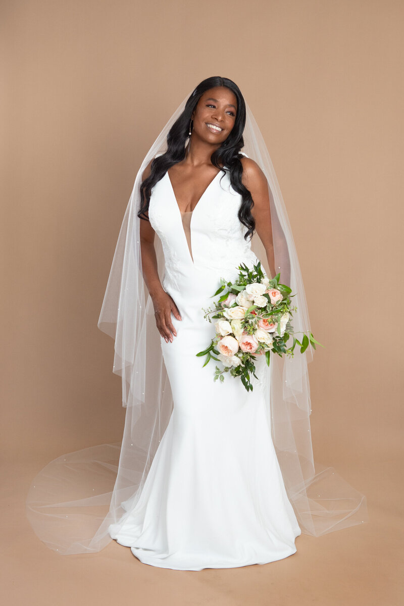 Bride wearing a cathedral length veil with blusher and pearls, and holding a white and blush bouquet