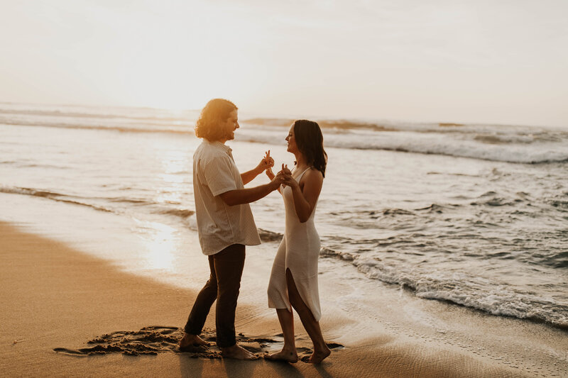 Couple in white dance on beach at sunset