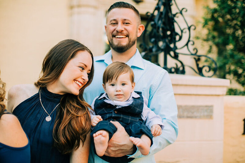 Orlando Reiki-certified healer, Brandi of the Intuitive Momma, stands next to husband holding son as they all smile.