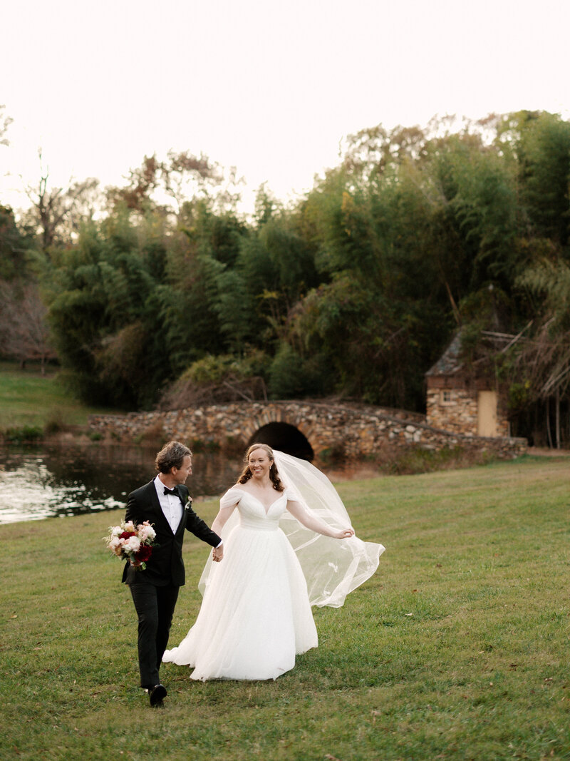 November wedding at Graylyn Estate, designed and planned by Charming Carolina — bride and groom holding hands during golden hour portraits on the estate grounds.
