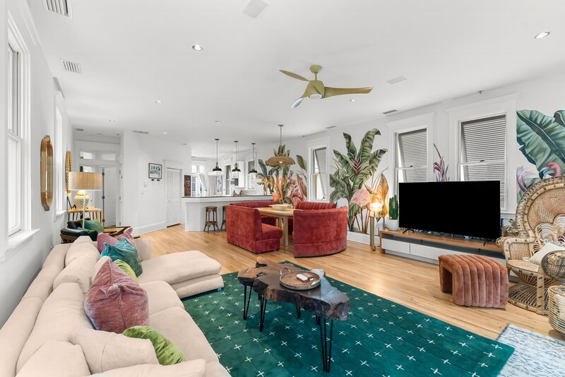 Expansive open floor plan with tropical murals, chic furniture, and easy flow from kitchen to living room at The Florida House, a 30A area rental close to Santa Rosa Beach.