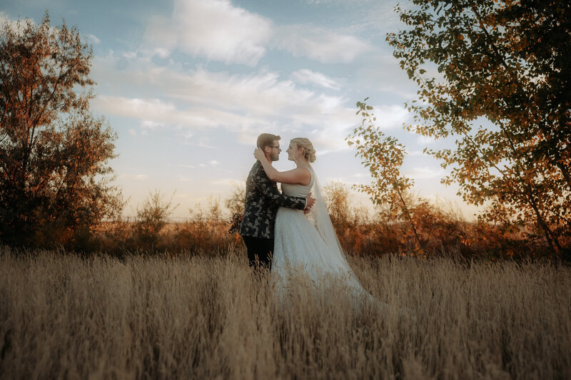 The photographer is crouched on a grassy hill with a lake behind her. She's holding a camera and looking to the right.