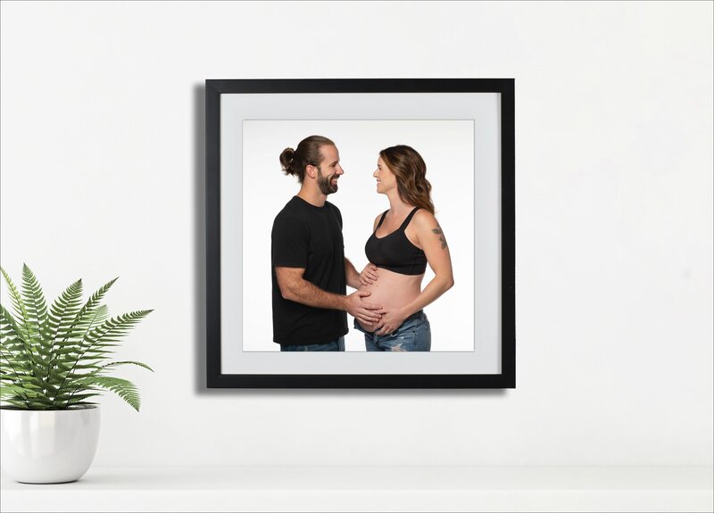 Rock Hill  maternity framed in black mocked up on a wall in their home with a fern plant  on the left