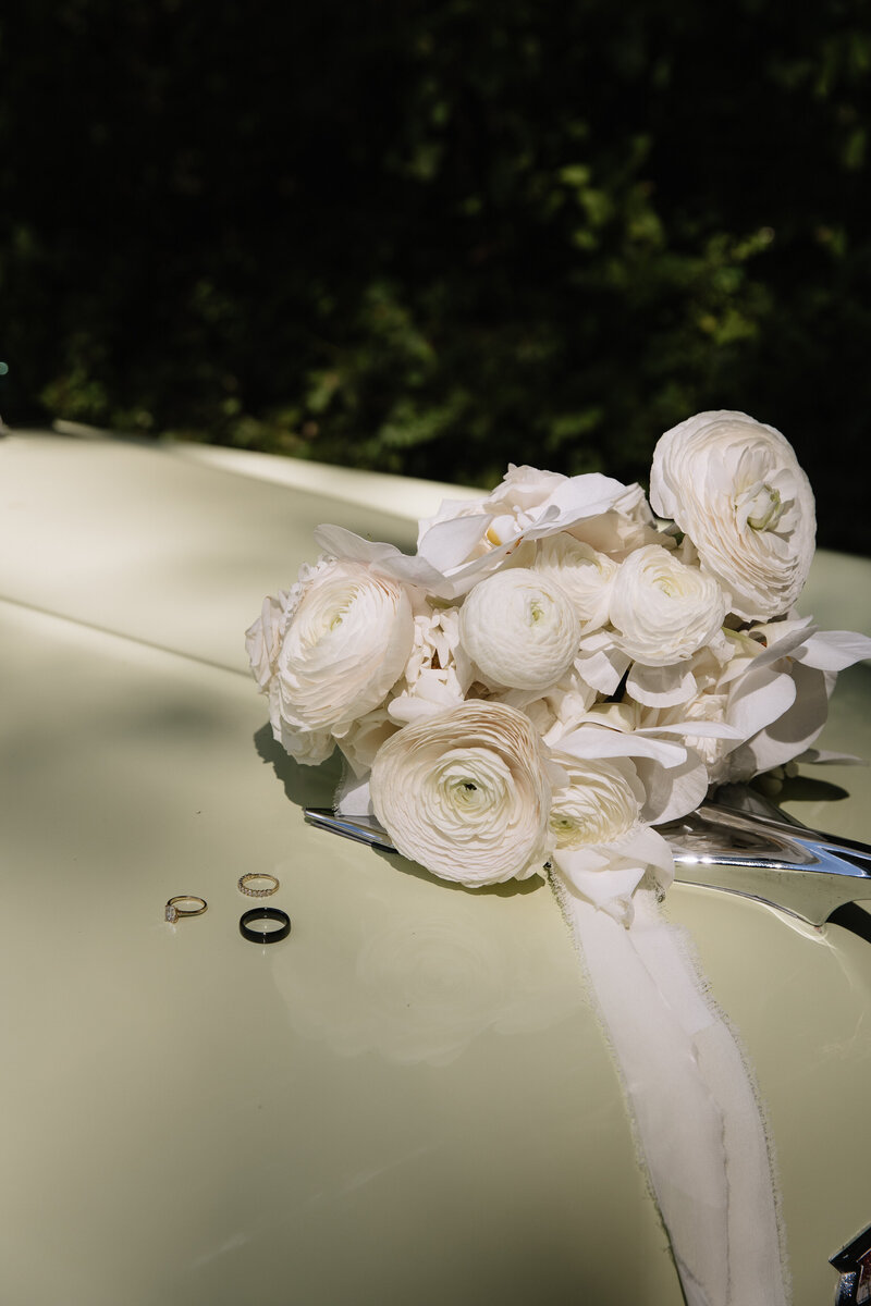 Flat lay of wedding rings on a chrome bumper of a classic car during spring Washington wedding