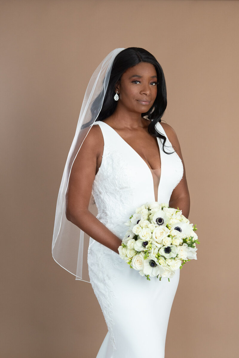 Bride wearing a fingertip veil with ribbon edge and holding a white and black bouquet
