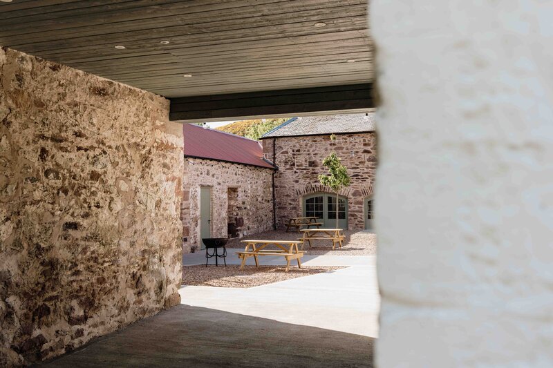 An old barn courtyard is photographed through an entrance way. The space is newly renovated.