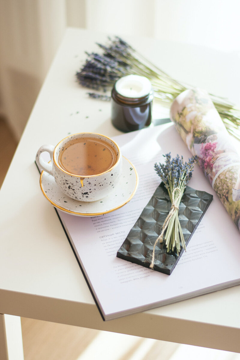 Hailey Ann Co Bookkeeper and somatic money coach for entrepreneurs. Desk with tea, chocolate, lavender, book and candle