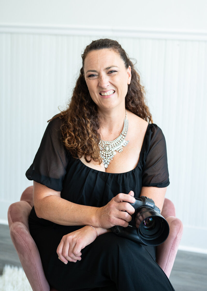 photographer holding camera infront of white wall