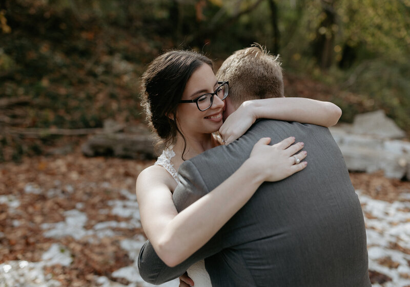 A couple embracing on another with fall leaves on the ground around them.