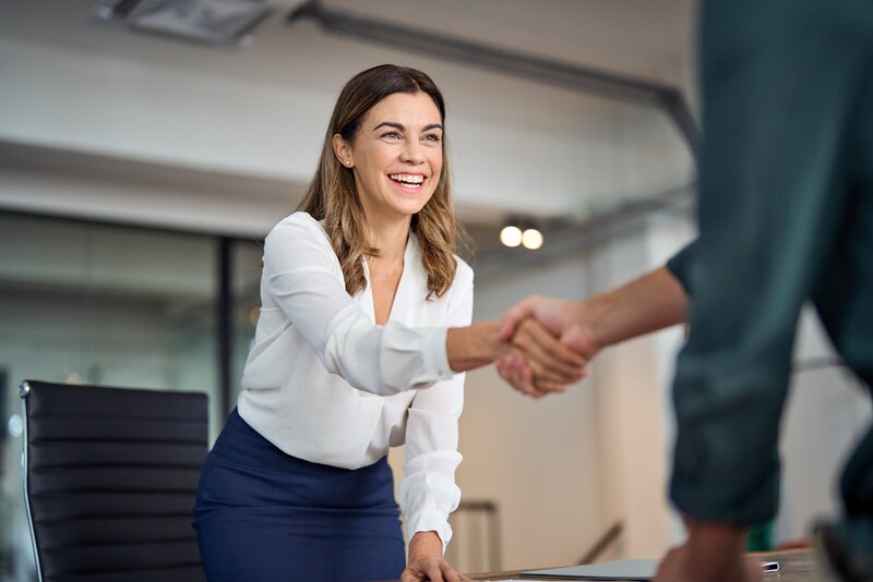 Professional woman smiling and shaking hands during a business meeting