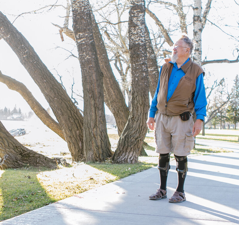 An elderly man with knee osteoarthritis walking in the park while wearing the Terminator knee brace from Lethbridge Orthotics.