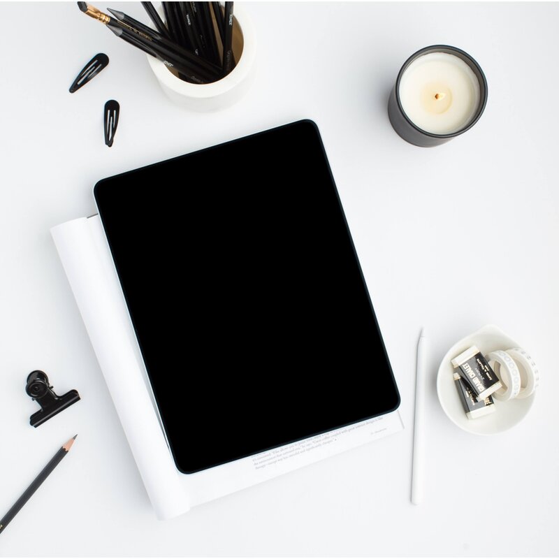 ipad on table with candle and black pencils in a pencil holder