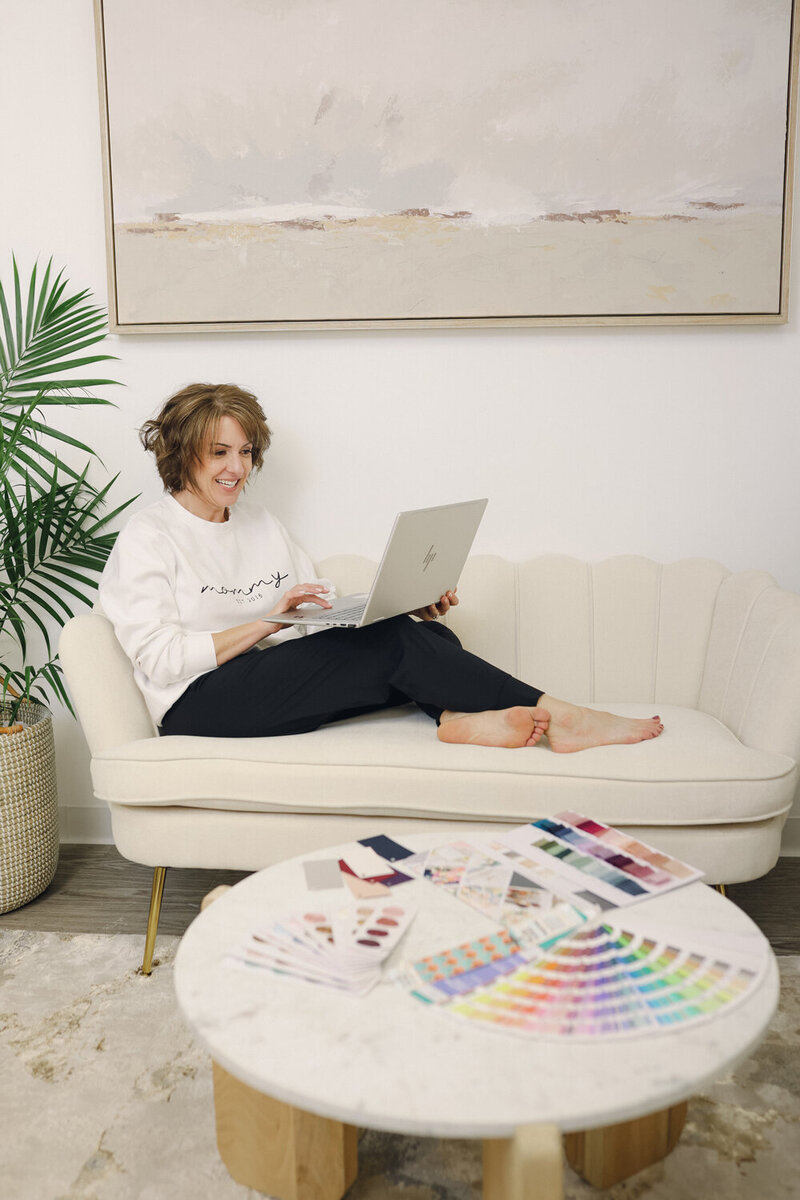 woman sitting on couch working on laptop