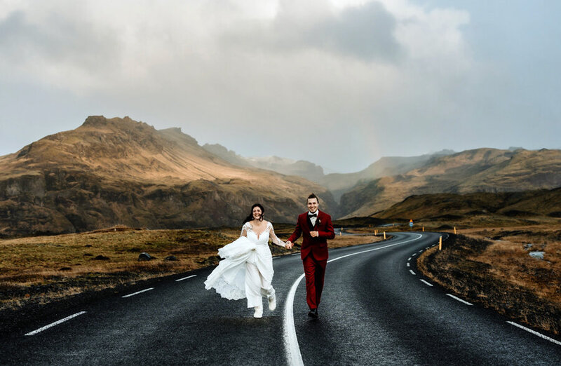 bride and groom are running on an icelandic road on their elopement day
