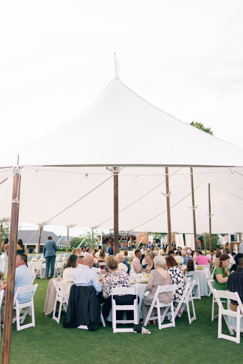Guests sit at white tables under sailcloth tent at the Boonsboro country club