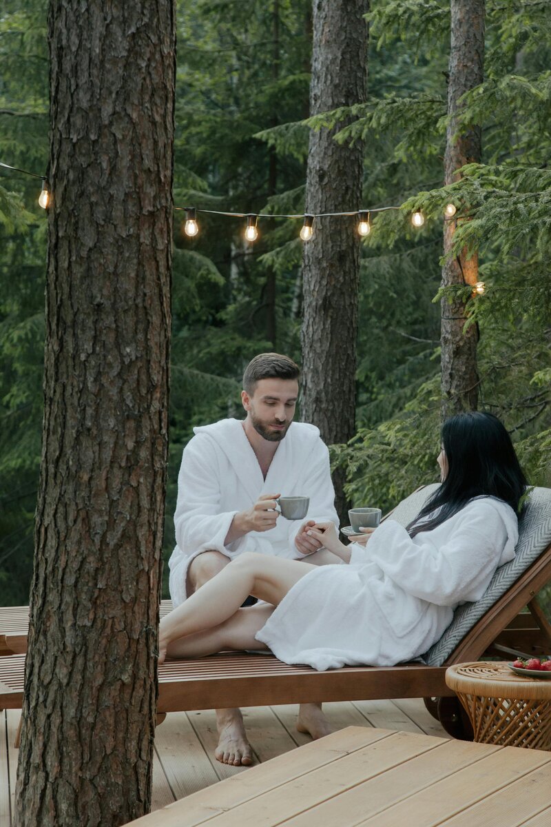 two people in white robes drinking coffee in the woods