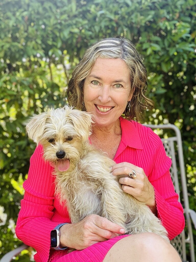 Playful, nurturing moment of Laura Kate with her dog Gabi, reflecting connection, love, and the heart-centered energy behind her work