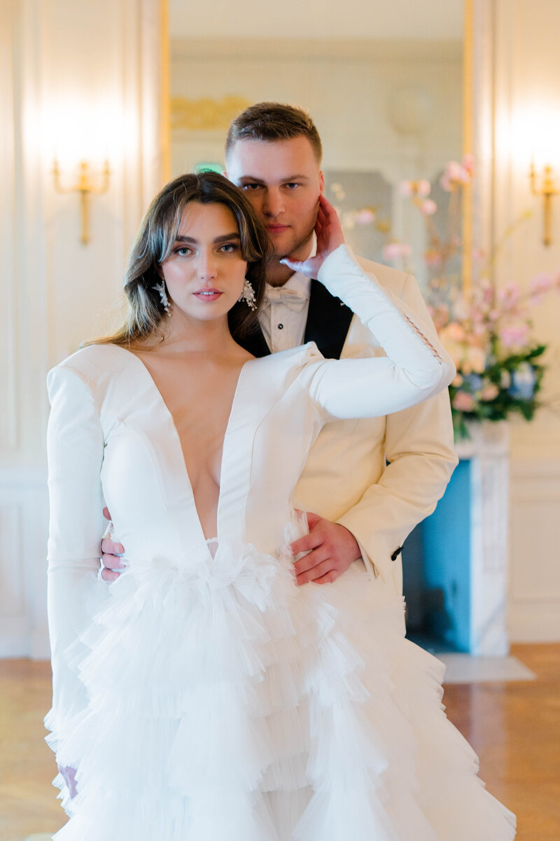 Newport Wedding Photographer | Rhode Island Caprio Captured Photography | Bride Wearing A V-Neck Gown Stands In Front Of Groom Holding Her Waist
