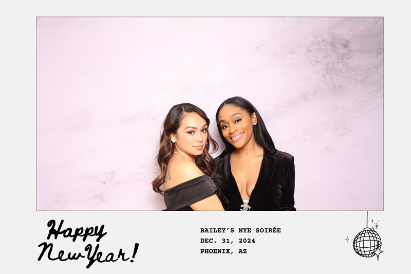 Two women smiling joyously in Always Present photo booth with minimal backdrop