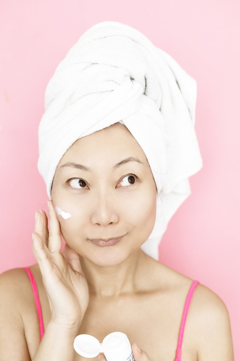 woman with clear skin, eyes closed, hand brushing face