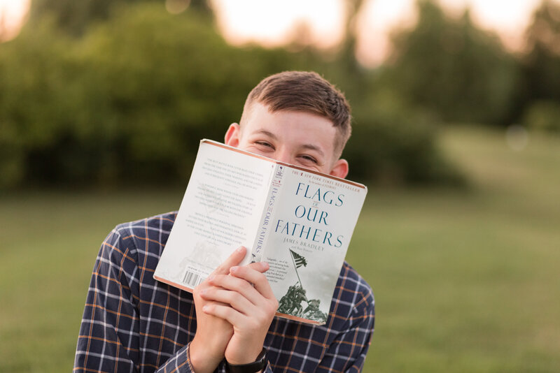 Senior boy holding the book  Flags of Our Fathers and smiling at the camera