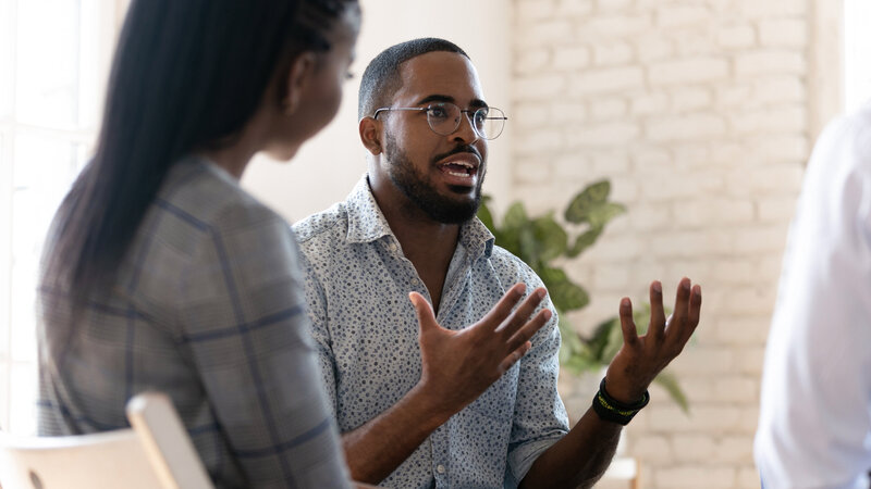 Man hand raised speaking in group therapy