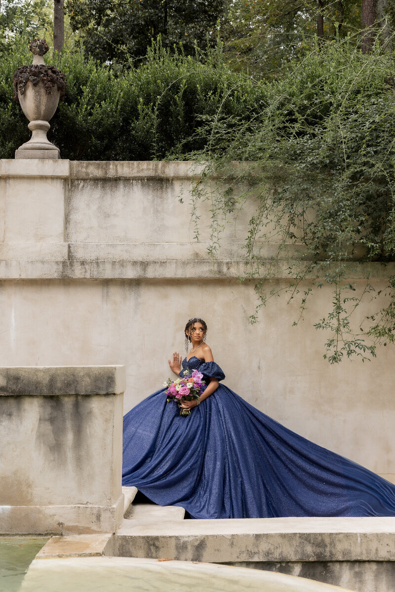 woman in quinceanera dress standing in front of large stone building