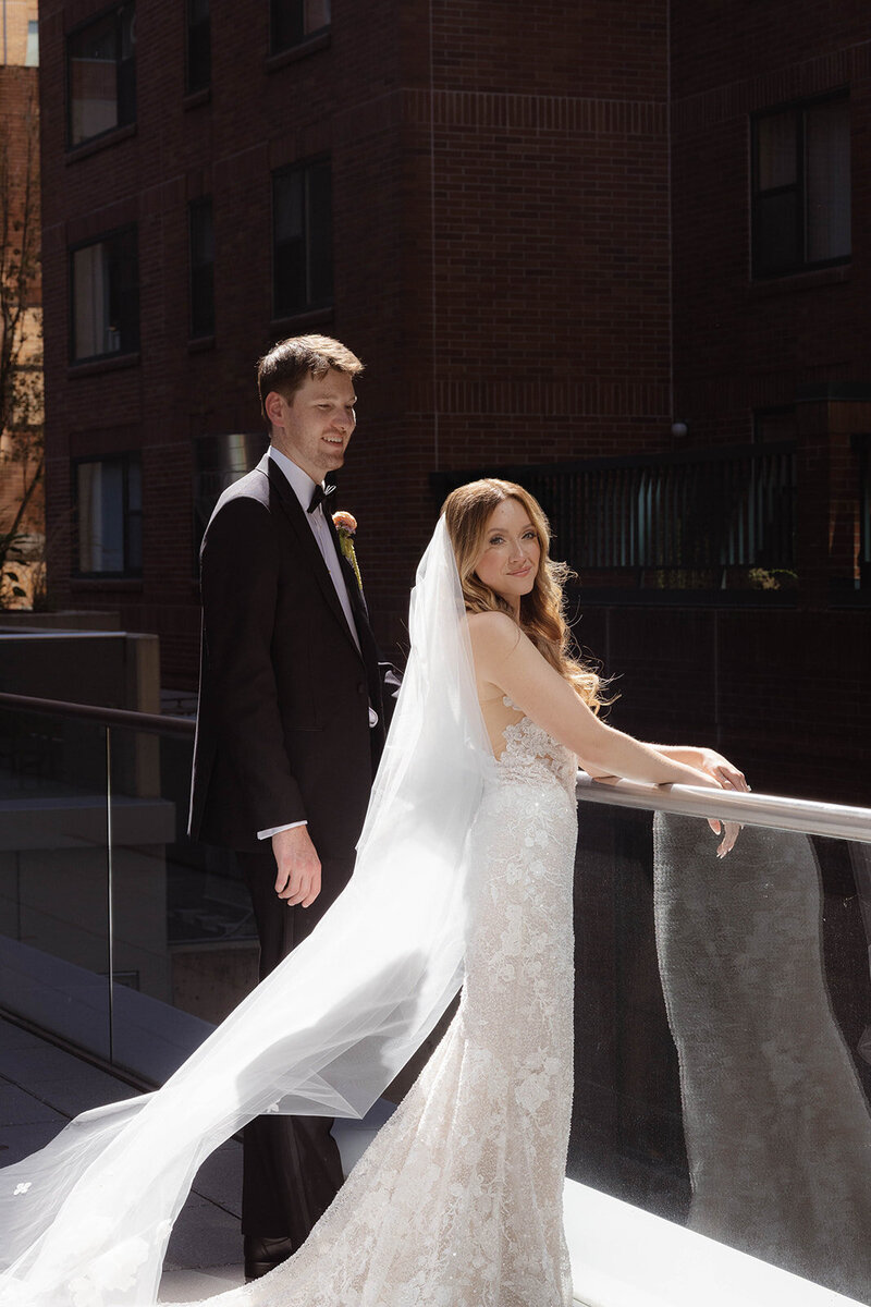 bride looking at groom in front of a column
