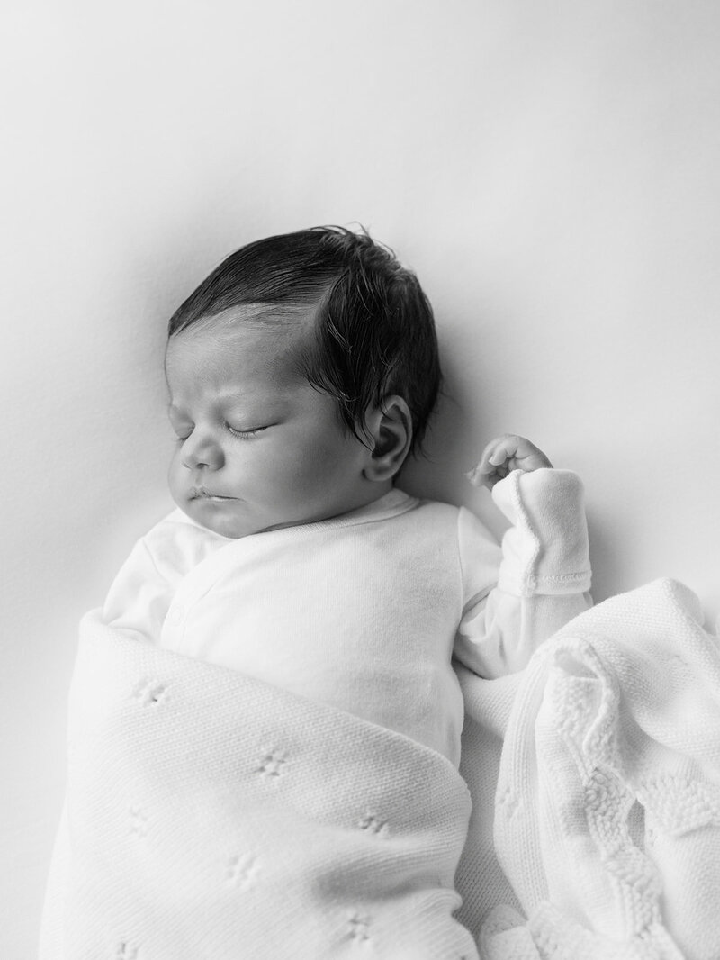 A newborn sleeping while wrapped in a blanket by Katie Stansfield Photography, a Richmond newborn photographer.