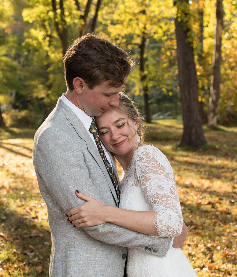 The groom is hugging his wife with the tress and sun in the background. This photo was taken by Mason Jesmer Photography.