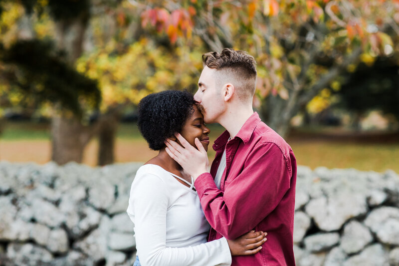 couple kissing forehead in autumn scene