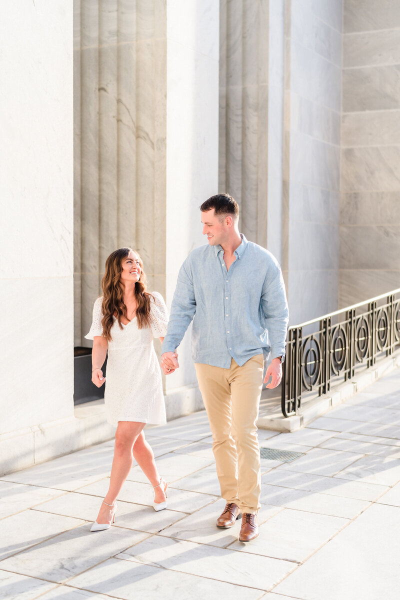 An engaged couple hold hands and smile during their downtown Columbus engagement shoot