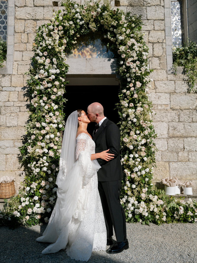 Wedding reception, white table, white chairs, the entire ceiling is covered with white florals and greenery.