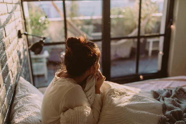 woman snuggled in bed looking out the window