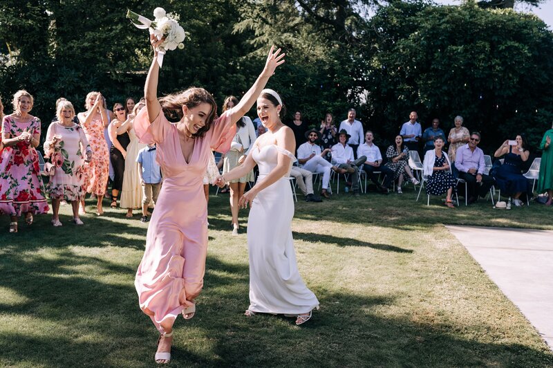 bridesmaid in pink blak dress catches white bouquet at christchurch wedding