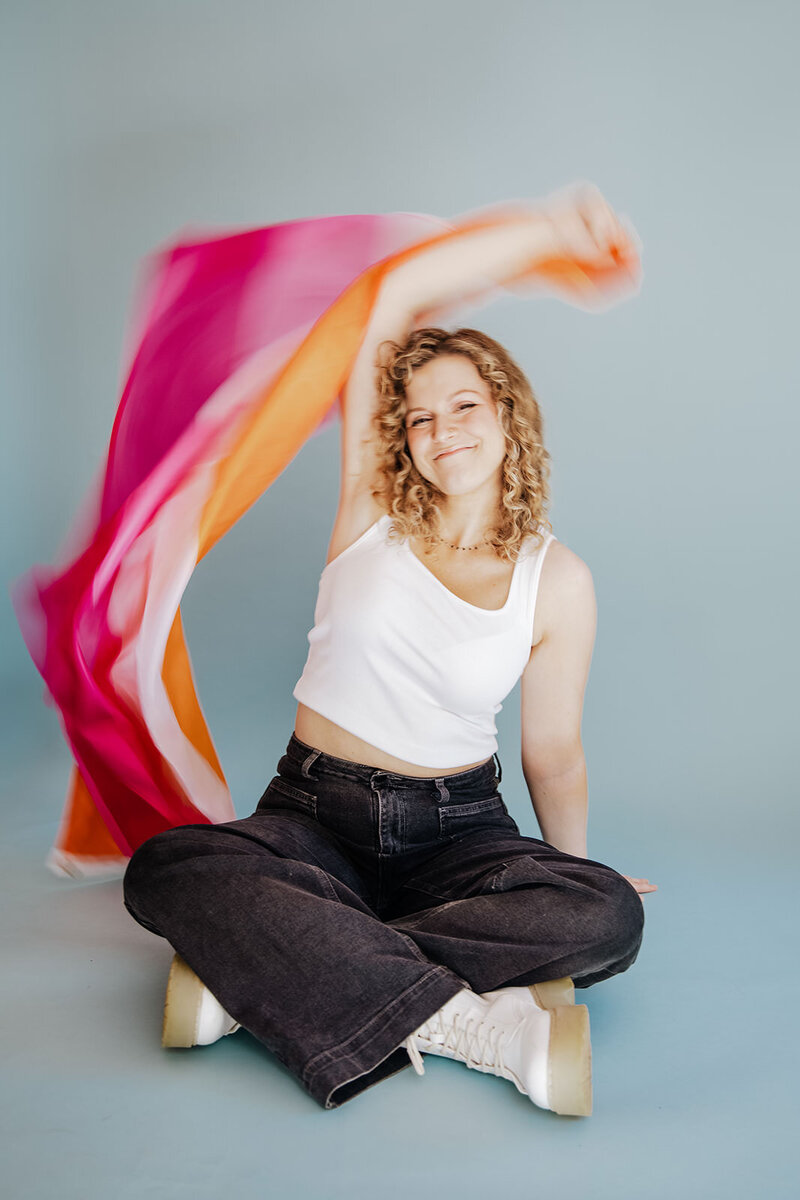Megan Morris sits cross legged and flies the Lesbian flag behind her