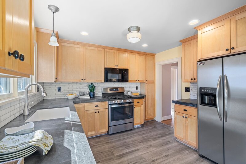A kitchen featuring brown cabinets and marble countertops.